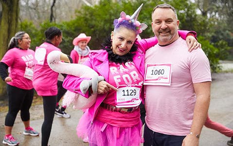 Race for Life runners wearing pink t-shirts and accessories including a pink unicorn headband, flamingo and cowboy hat.